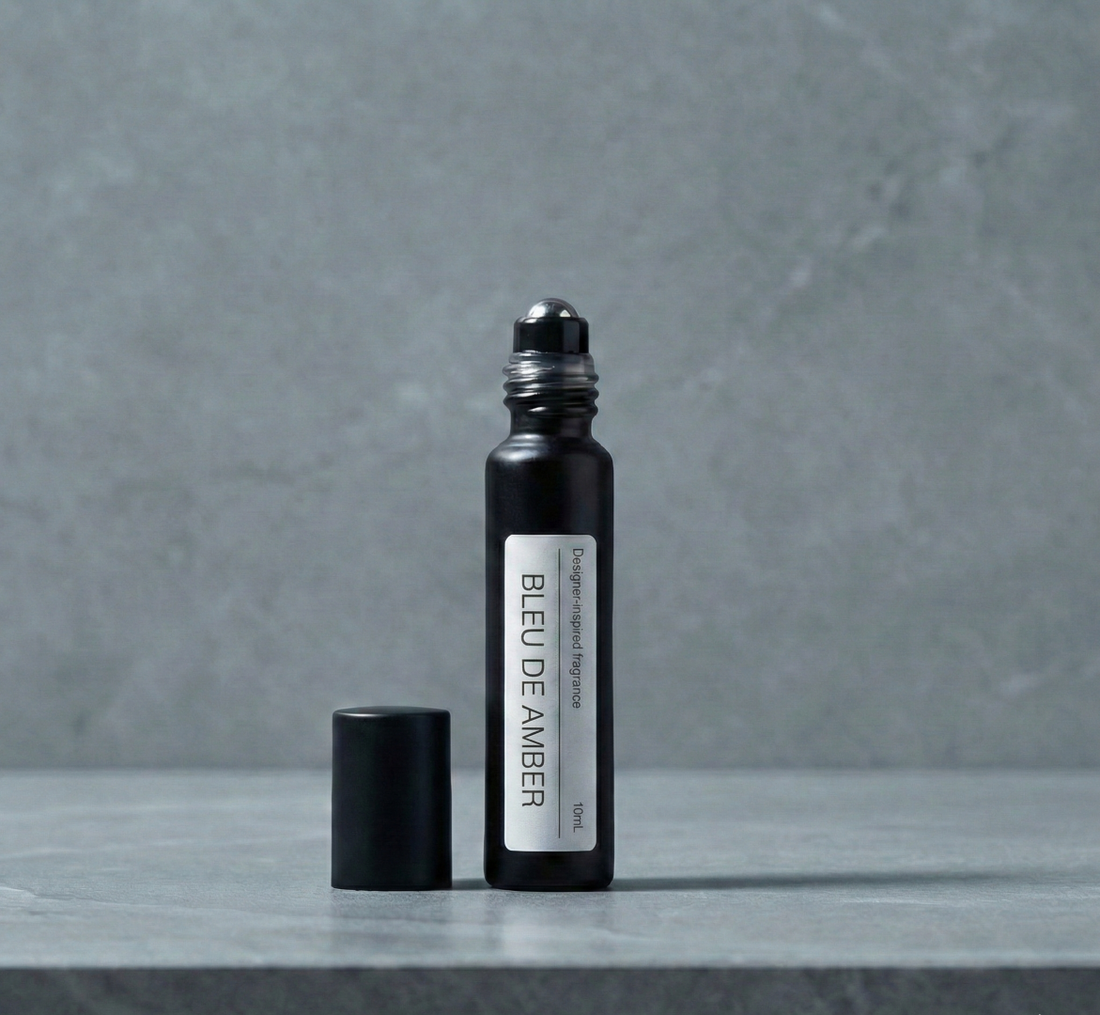 Close up of a luxury glass perfume roll-on bottle representing the best Bleu de Chanel dupe next to fresh grapefruit and sandalwood.